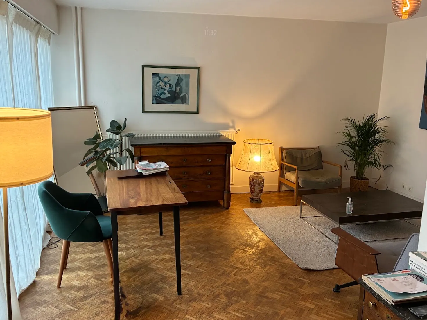 La salle de consultation : bureau en bois, fauteuils et lampes à la lumière chaleureuse, parquet ancien